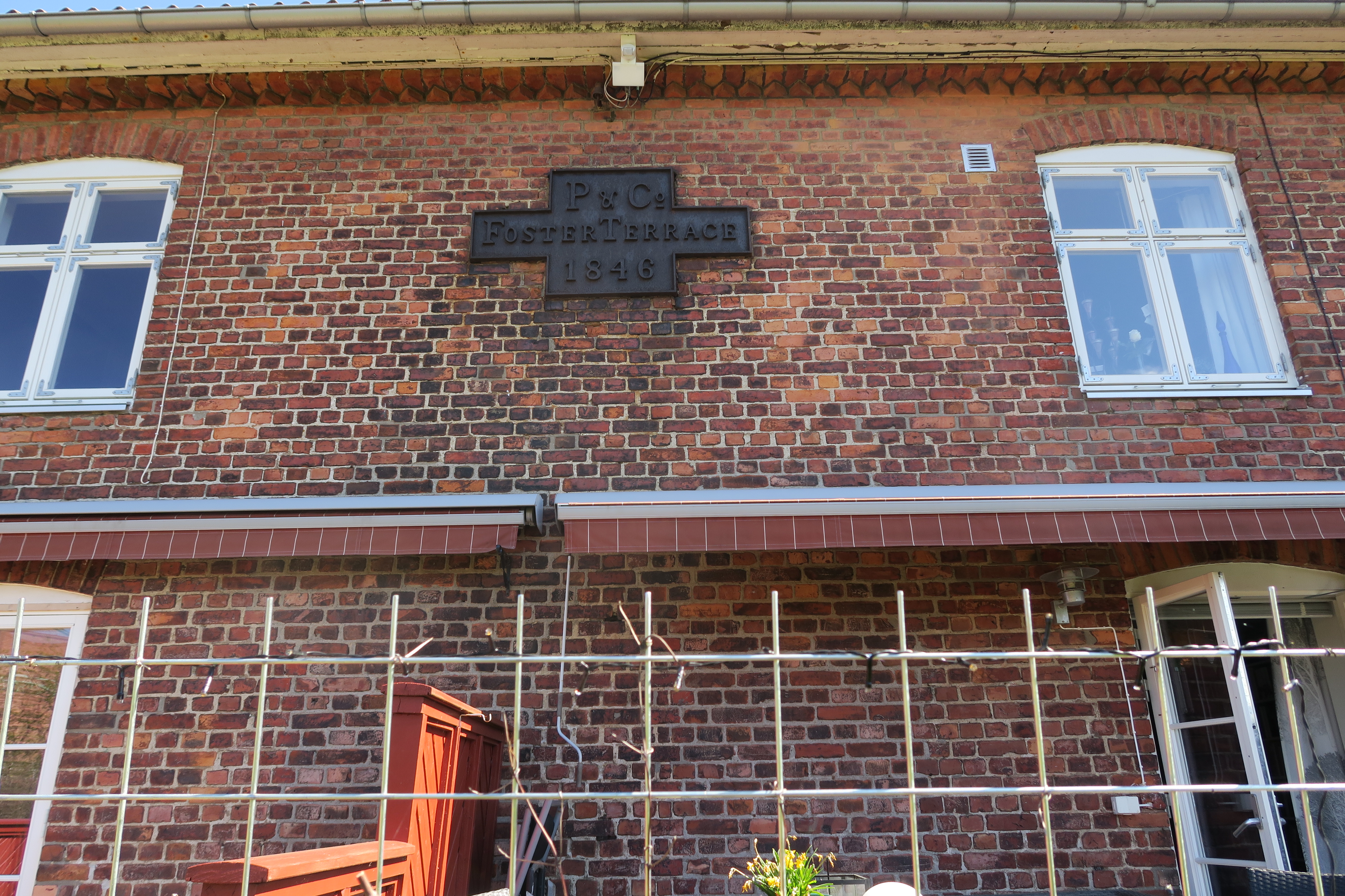 På sørveggen til Hanna B. Gansmoes seksjon i Tarris, henger det originale skiltet som tydelig viser når huset ble bygget og av hvem.